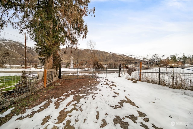 snowy yard featuring a mountain view and a rural view