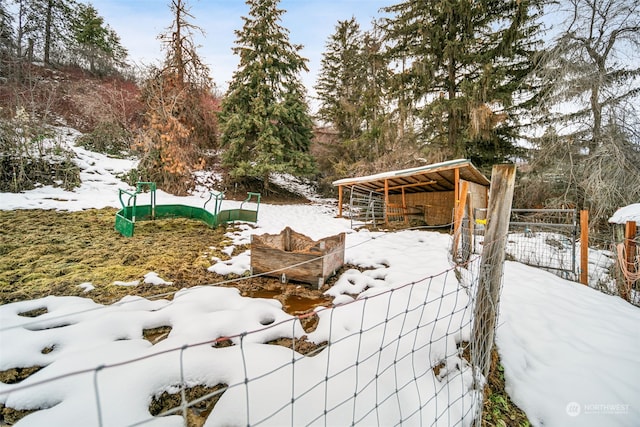 yard layered in snow with an outbuilding