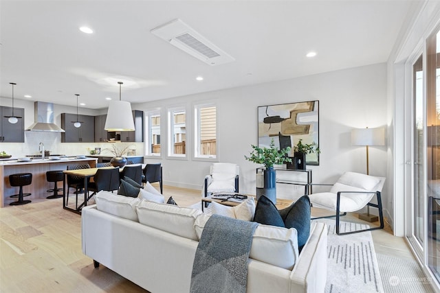 living room with plenty of natural light, light hardwood / wood-style floors, and sink