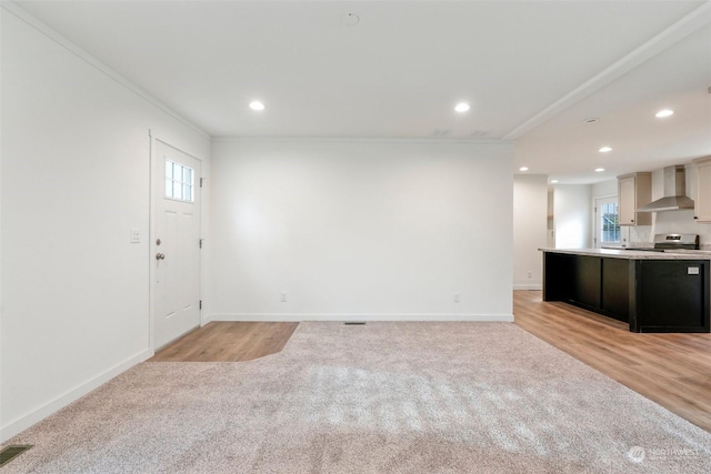 unfurnished living room with crown molding and light colored carpet