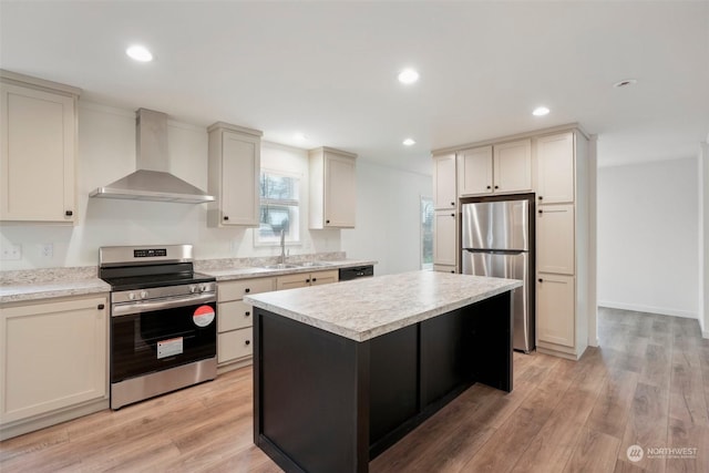 kitchen featuring a center island, wall chimney exhaust hood, stainless steel appliances, and light wood-type flooring