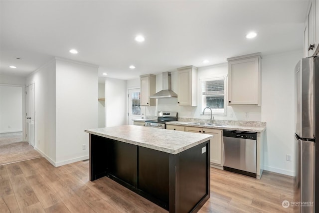 kitchen with sink, a center island, stainless steel appliances, wall chimney range hood, and light hardwood / wood-style flooring