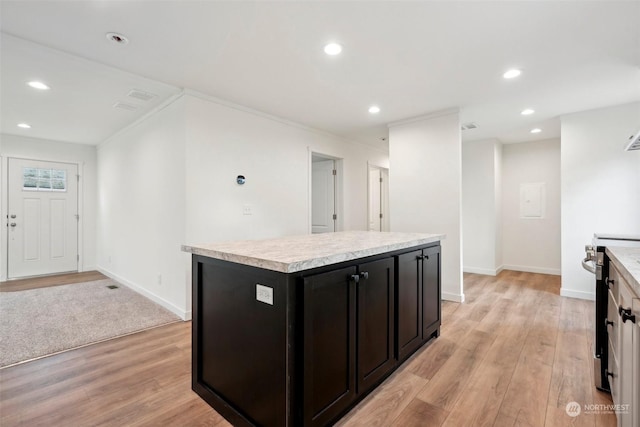 kitchen with light wood-type flooring, a kitchen island, crown molding, and electric stove