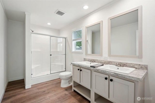 bathroom with hardwood / wood-style floors, vanity, toilet, ornamental molding, and a shower with shower door