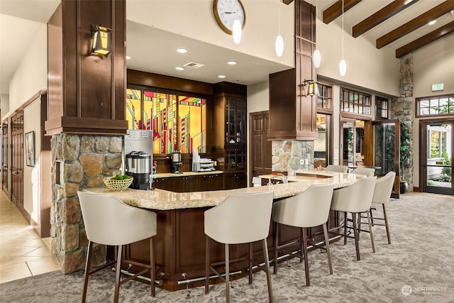 bar with pendant lighting, a high ceiling, light stone countertops, light colored carpet, and beamed ceiling