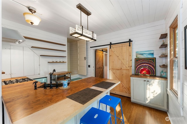 dining space featuring wooden walls, a barn door, and light hardwood / wood-style flooring