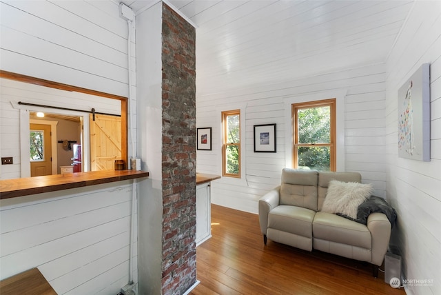 living room with wood-type flooring, wooden walls, and a barn door