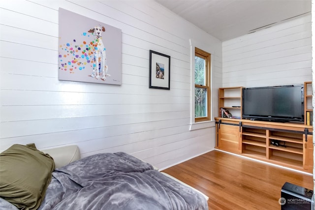 bedroom with hardwood / wood-style flooring and wood walls