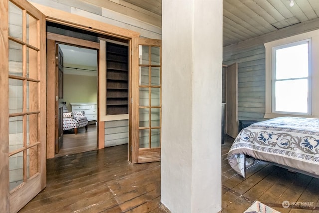 bedroom with dark hardwood / wood-style flooring, wooden walls, and a closet