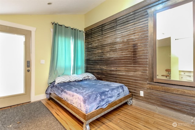 bedroom with wooden walls and hardwood / wood-style flooring