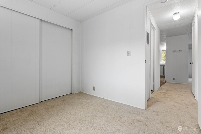 unfurnished bedroom featuring light colored carpet and a closet