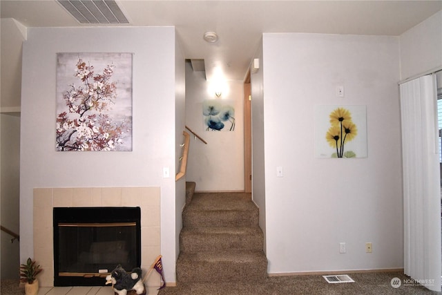 stairway with a tile fireplace and carpet floors