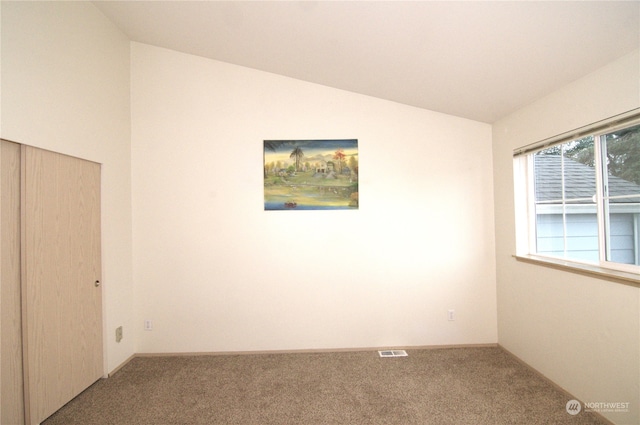 carpeted spare room featuring vaulted ceiling