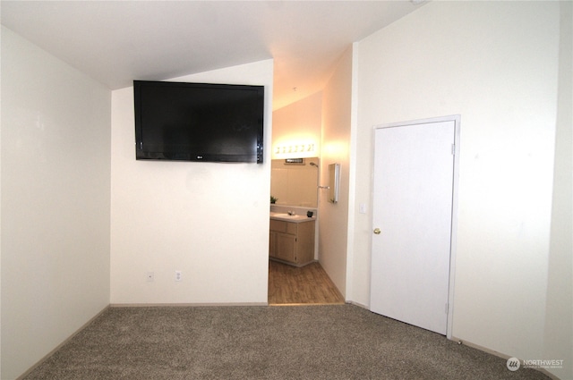 unfurnished bedroom with lofted ceiling, ensuite bath, sink, and carpet