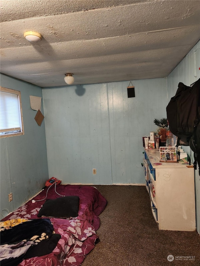 carpeted bedroom with a textured ceiling and wooden walls