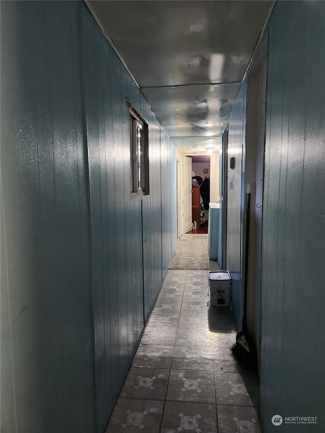 hall with dark colored carpet and wooden walls