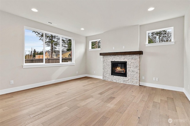 unfurnished living room featuring a fireplace and light hardwood / wood-style floors