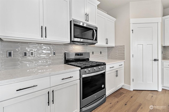 kitchen with white cabinets, decorative backsplash, light stone countertops, and appliances with stainless steel finishes