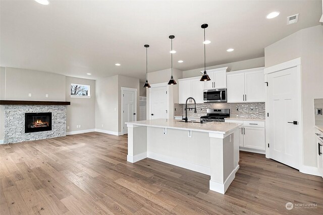 kitchen featuring white cabinets, appliances with stainless steel finishes, a kitchen island with sink, and sink