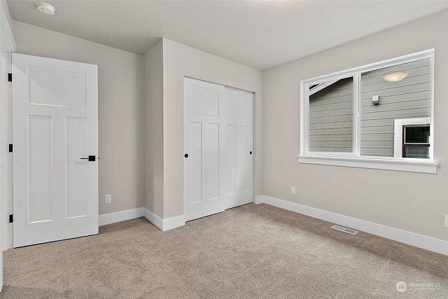 unfurnished bedroom featuring a closet and light colored carpet