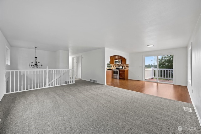 unfurnished living room with light colored carpet and a chandelier