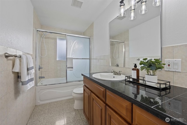 full bathroom featuring tile walls, vanity, enclosed tub / shower combo, and toilet