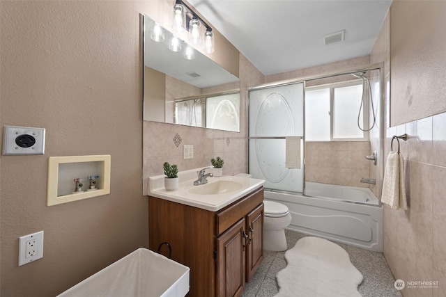 full bathroom with toilet, vanity, shower / bath combination with glass door, and tile walls