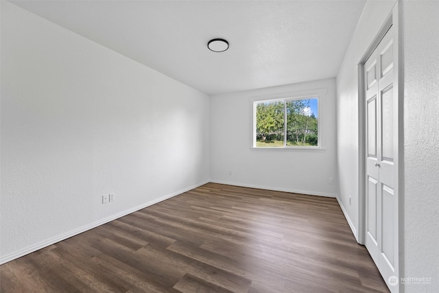 unfurnished bedroom with dark wood-type flooring and a closet