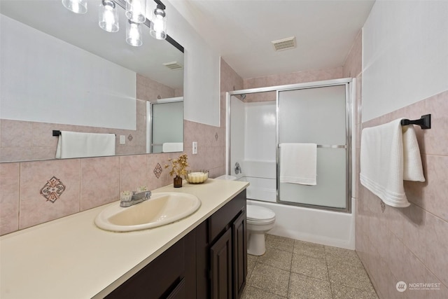 full bathroom featuring tile walls, vanity, shower / bath combination with glass door, and toilet