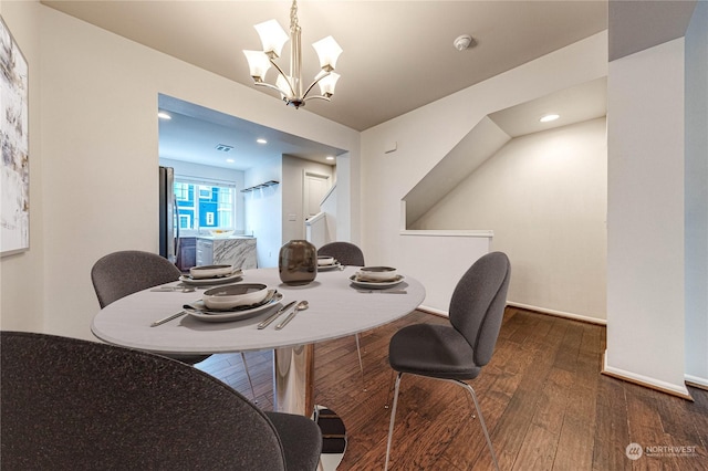 dining space with dark hardwood / wood-style floors and an inviting chandelier