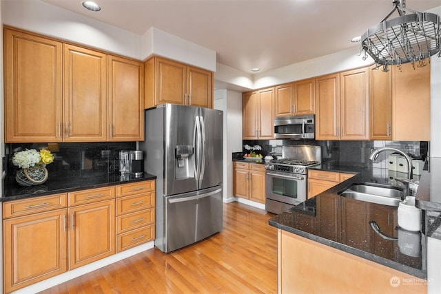 kitchen featuring appliances with stainless steel finishes, decorative light fixtures, dark stone countertops, sink, and backsplash