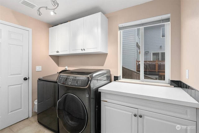 washroom with light tile patterned floors, separate washer and dryer, and cabinets