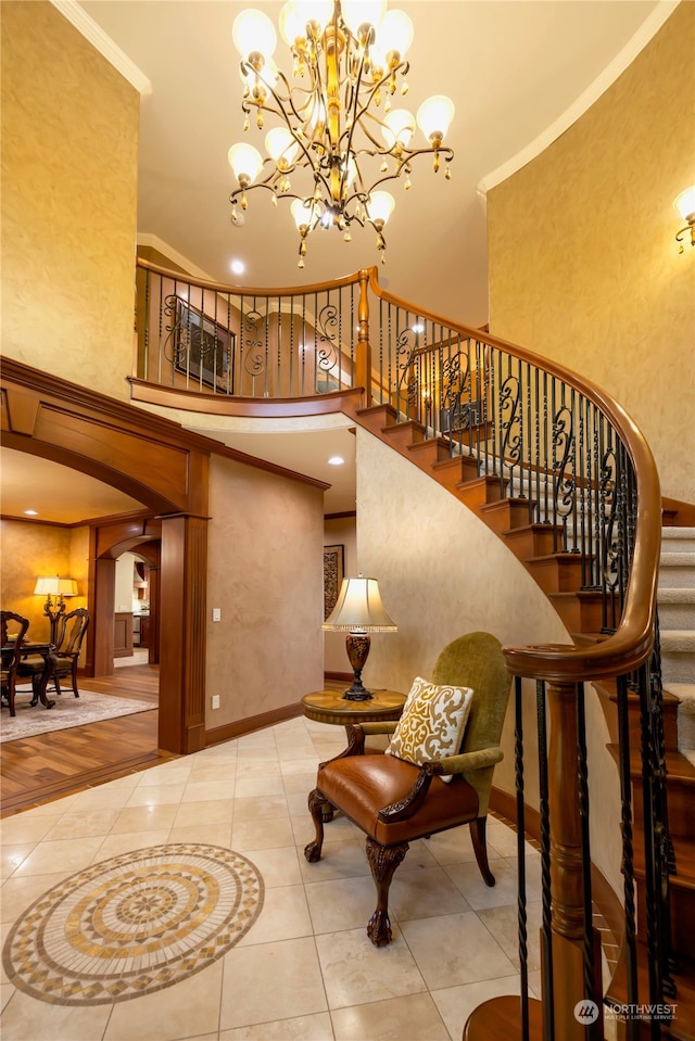 stairway featuring tile patterned floors, a notable chandelier, crown molding, and a high ceiling