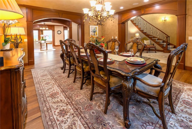 dining area with a notable chandelier, ornate columns, and light hardwood / wood-style flooring