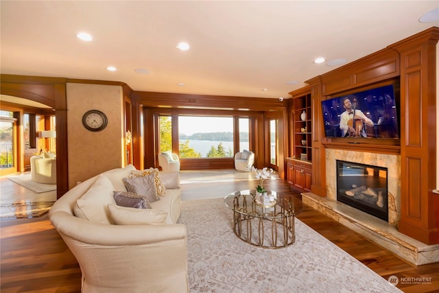 living room featuring dark hardwood / wood-style flooring, built in features, and crown molding