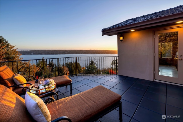 patio terrace at dusk with a balcony and a water view