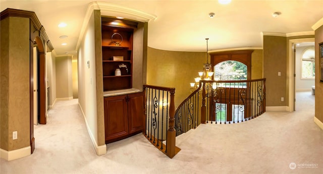 hall with built in features, light colored carpet, ornamental molding, and a chandelier