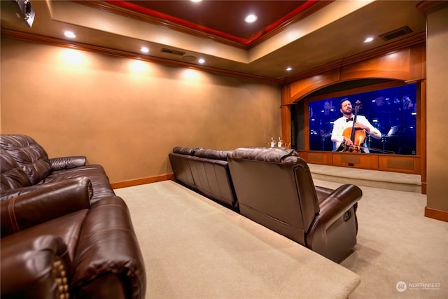 carpeted home theater room with a tray ceiling and ornamental molding