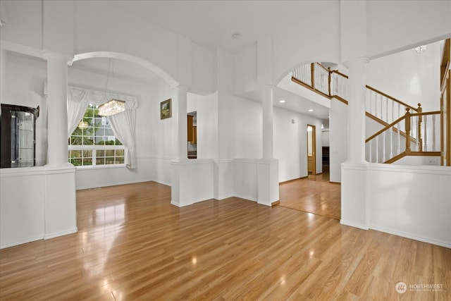 unfurnished living room featuring a chandelier, a high ceiling, and light hardwood / wood-style flooring