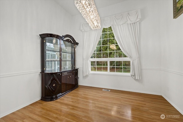 unfurnished dining area with a chandelier and light wood-type flooring