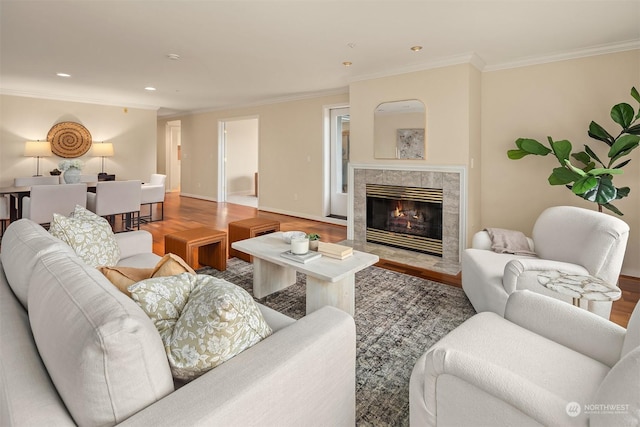 living room featuring a tile fireplace, ornamental molding, and hardwood / wood-style flooring