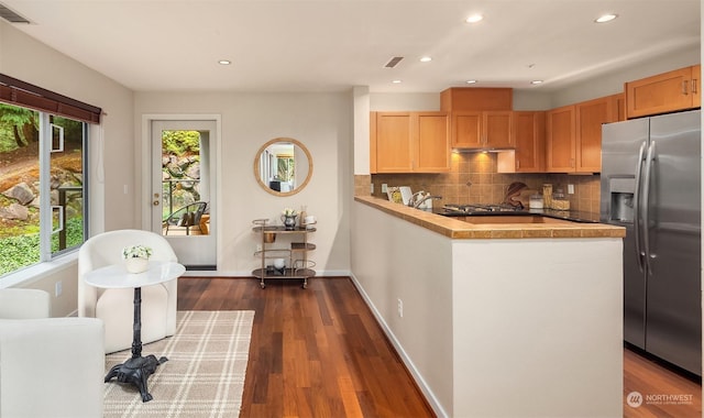 kitchen featuring wood counters, kitchen peninsula, backsplash, dark wood-type flooring, and stainless steel fridge with ice dispenser