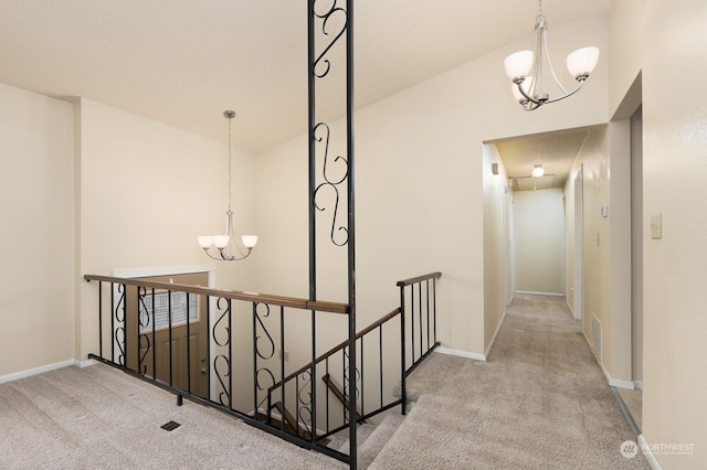 hallway with light colored carpet and a chandelier