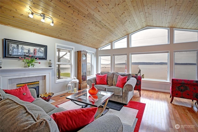 living room with plenty of natural light, light wood-type flooring, wooden ceiling, and a tile fireplace