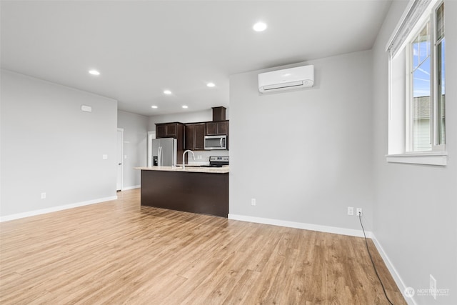 kitchen featuring plenty of natural light, an AC wall unit, light hardwood / wood-style flooring, appliances with stainless steel finishes, and dark brown cabinets