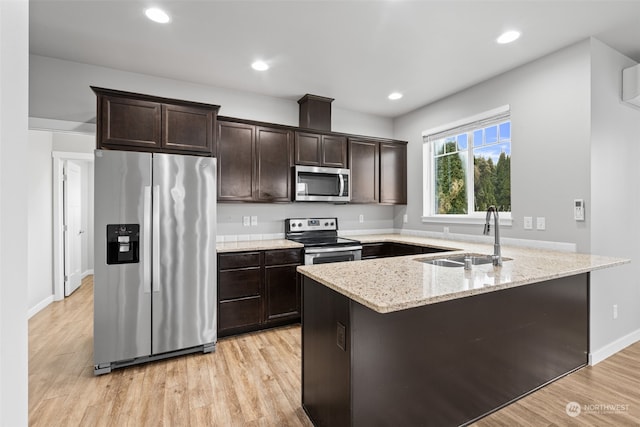 kitchen featuring light stone countertops, dark brown cabinets, stainless steel appliances, sink, and light hardwood / wood-style flooring