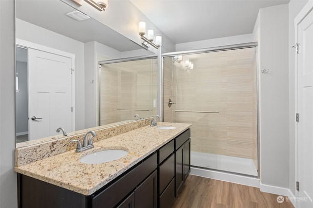 bathroom with wood-type flooring, vanity, and a shower with shower door