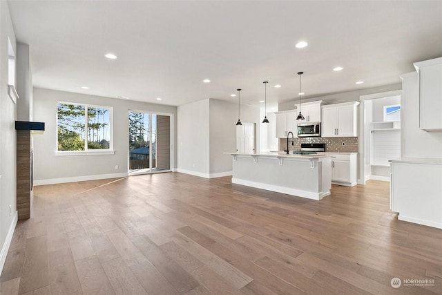 unfurnished living room with sink and light hardwood / wood-style floors