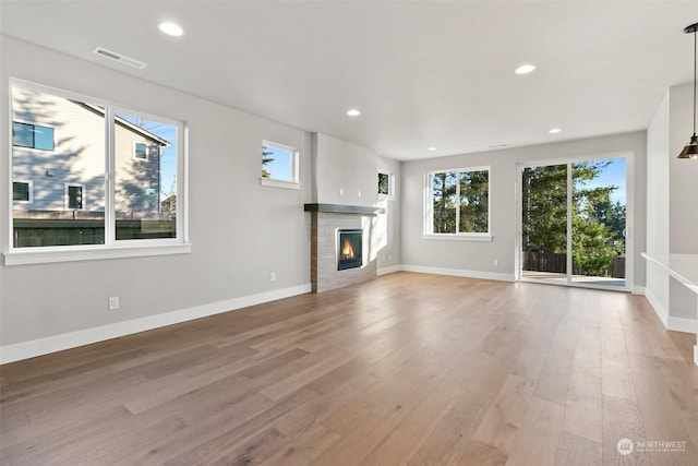 unfurnished living room with a fireplace, a wealth of natural light, and wood-type flooring