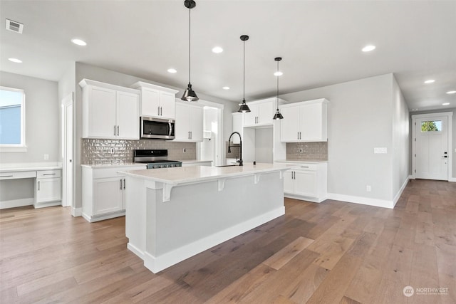 kitchen featuring white cabinetry, appliances with stainless steel finishes, and an island with sink